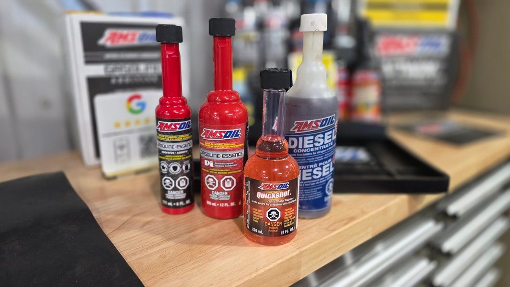 Gamme d'additifs carburant AMSOIL : bouteilles P.i. essence, Quickshot et additif diesel alignées sur un établi