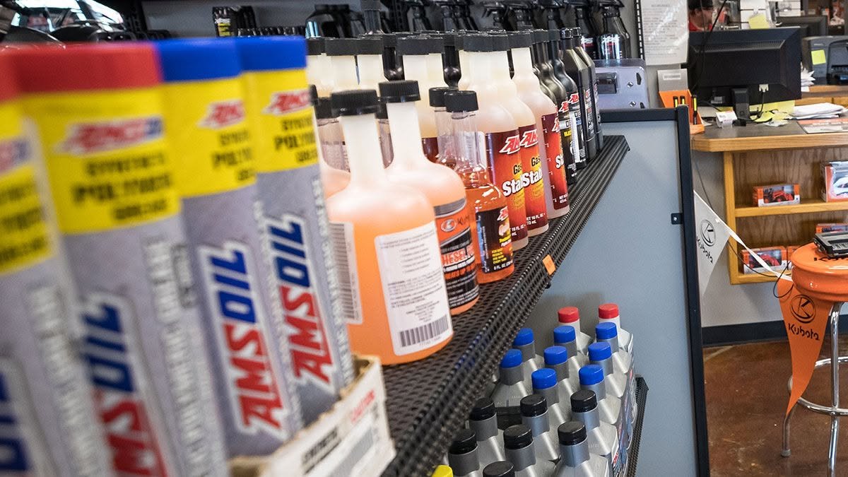 Présentoir de produits AMSOIL — graisses, additifs et huiles — au comptoir d'un commerce