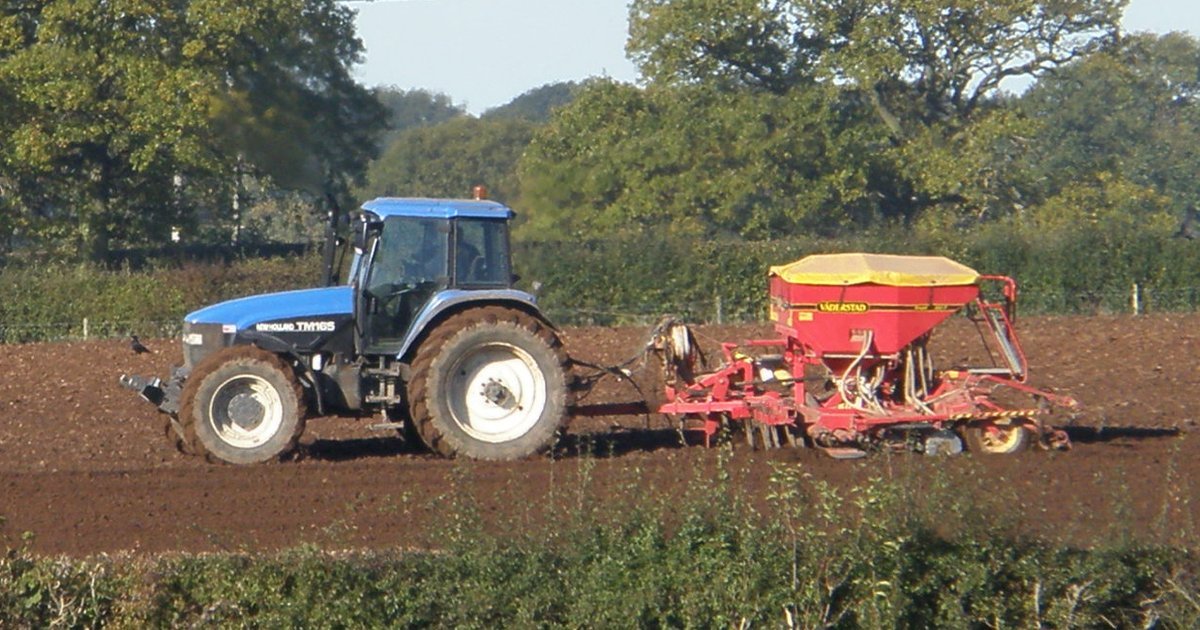 Tracteur New Holland TM165 tirant un semoir Väderstad dans un champ labouré